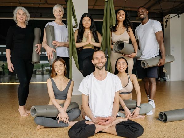 Diverse group of people smiling and preparing for a yoga class.